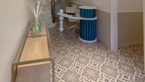 A hallway with patterned flooring, a staircase, and a reception desk with a blue accent.