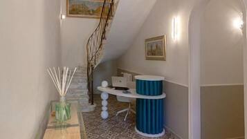 Un corridoio con pavimento decorato, una scala e una reception con un dettaglio blu.