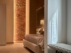 A bedroom with a brick wall, a bed, a hanging light fixture, and a partially visible window. - La Pépite (Viareggio)