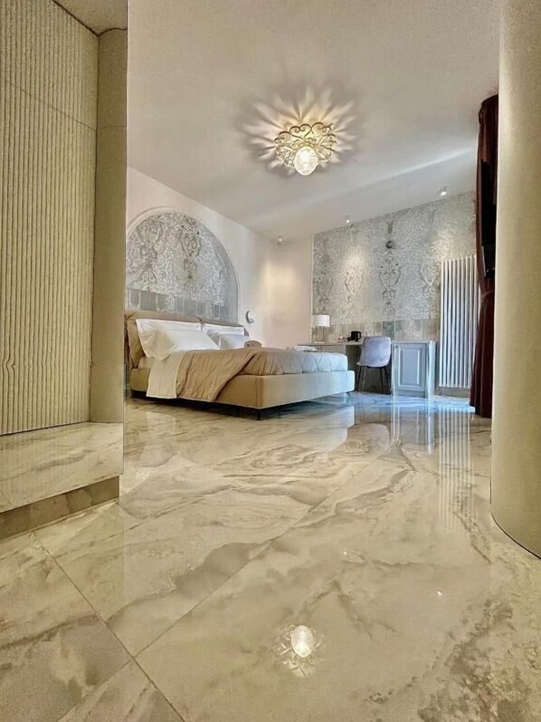 A spacious bedroom with a large bed, a decorative ceiling light, and a marble floor.