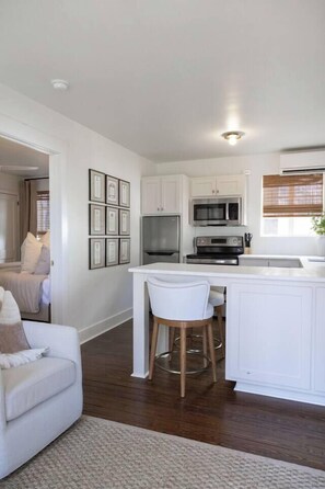 A modern kitchen with white cabinetry, stainless steel appliances, and a central island with stools.
