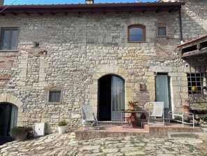 A stone building with a patio area featuring a table and chairs. - A charming two-room apartment surrounded by greenery on a farm just a short walk from the city (sesto fiorentino)
