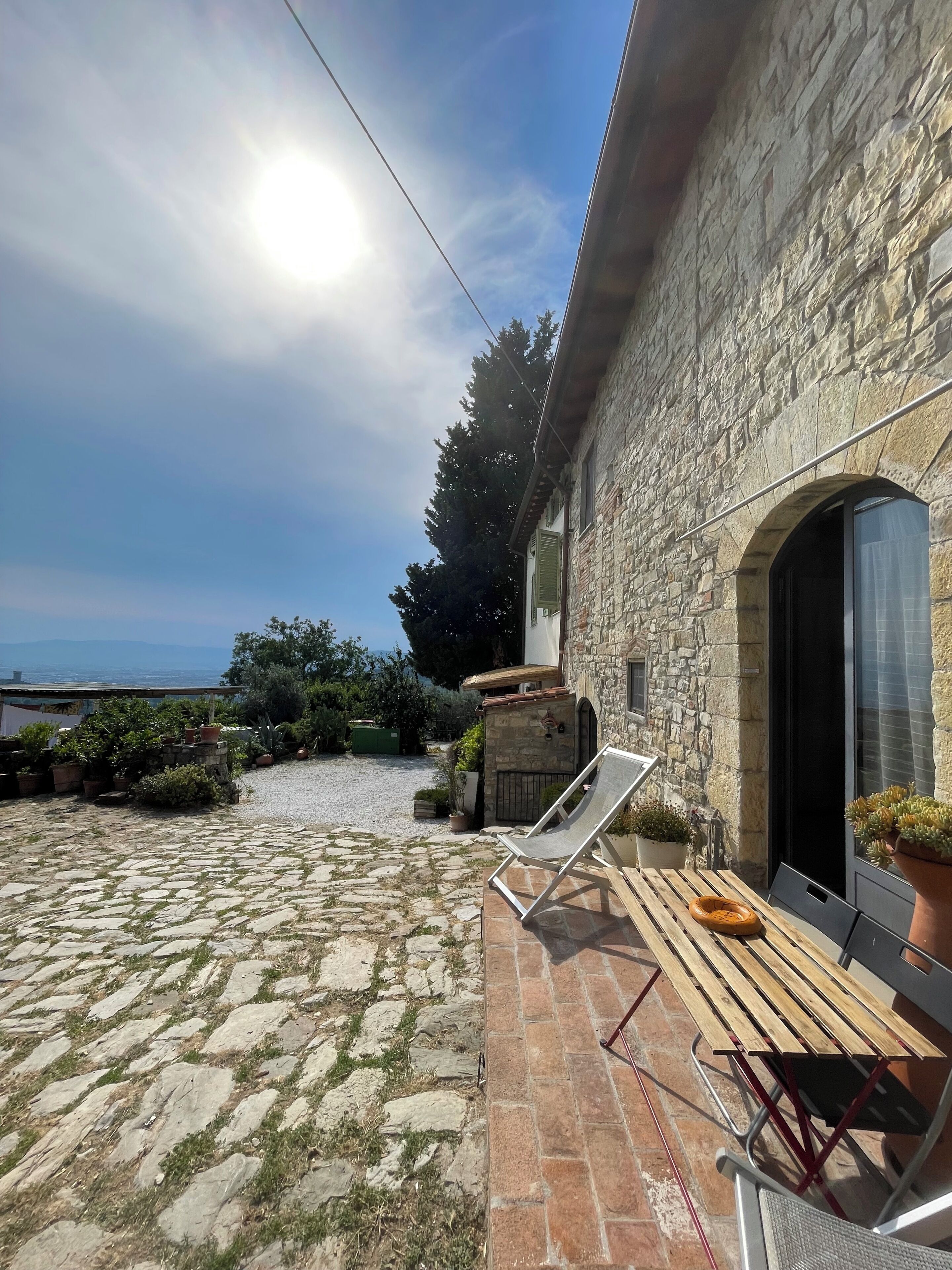 A stone building with a patio area, a lounge chair, and a view of the sea.