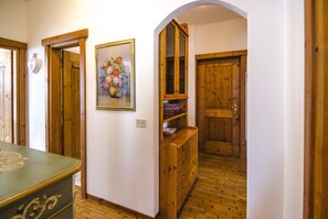 Ein Flur mit Holztüren, einem gerahmten Blumenbild und einer Holzkommode mit Spiegel.