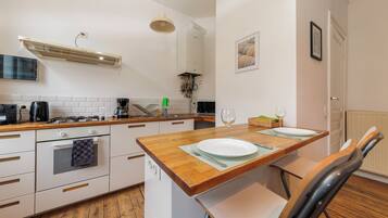 A modern kitchen with white cabinetry, a wooden countertop, and a dining area with a table set for two.
