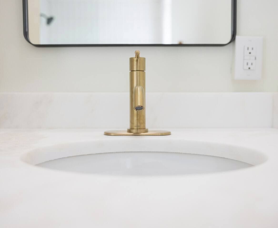 A bathroom sink with a gold faucet and a mirror above it.