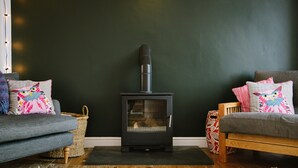 A cozy living room with a wood-burning stove, two sofas, and patterned cushions. - Stunning Apartment Near Fistral Beach (Newquay)