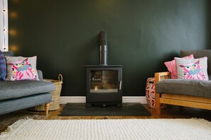 Ein gemütliches Wohnzimmer mit Kamin, zwei Sofas und gemusterten Kissen.