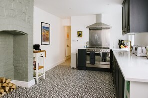 A modern kitchen with a large stove, a hanging pot rack, and a patterned floor. - Stunning Apartment Near Fistral Beach (Newquay)