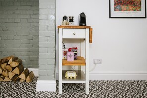 A white shelf with a drawer, holding various items including a coffee maker, a box of tea, and a small yellow container. - Stunning Apartment Near Fistral Beach (Newquay)