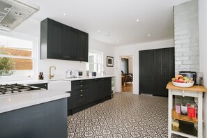 Une cuisine moderne avec des meubles de couleur sombre, une cuisinière à gaz et un carrelage décoratif.