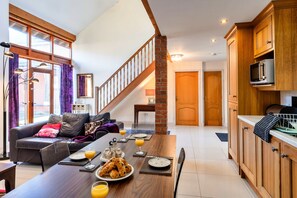 Eine moderne Küche mit Holzausstattung, ein Essbereich mit Frühstückstisch und eine Treppe, die zu einer weiteren Ebene führt.