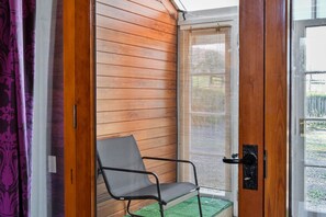 Ein Zimmer mit Holzboden, einem Stuhl, einer Tür und einem Fenster mit Jalousien.