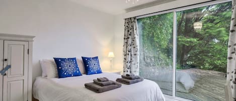 Un dormitorio con una cama grande, un armario, una araña y una ventana con cortinas, con vista a zonas verdes.