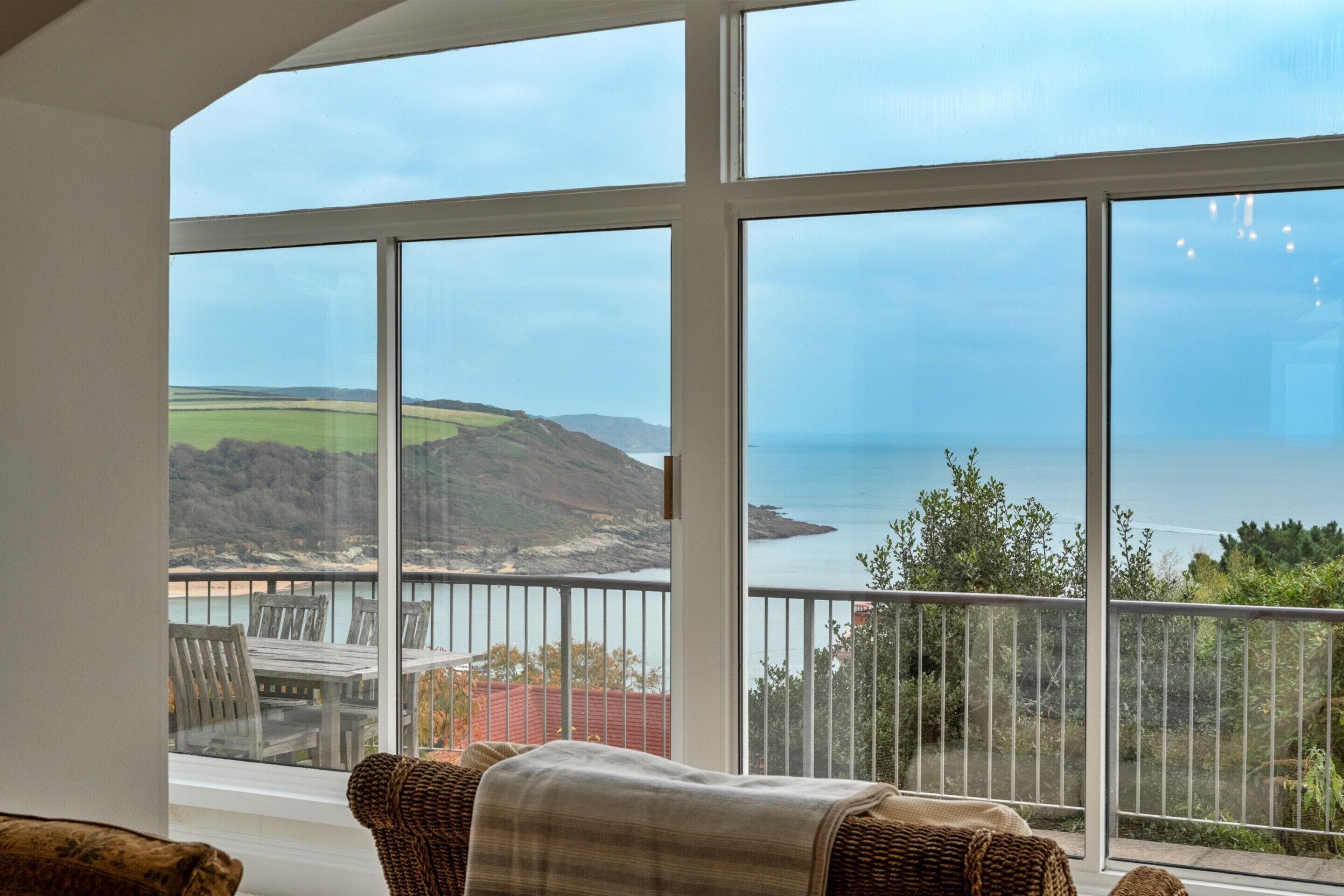 A room with a large window overlooking a coastal landscape.