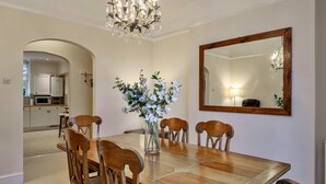 Ein Esszimmer mit einem Holztisch, Stühlen, einer Kristallleuchtre und einem Spiegel an der Wand.