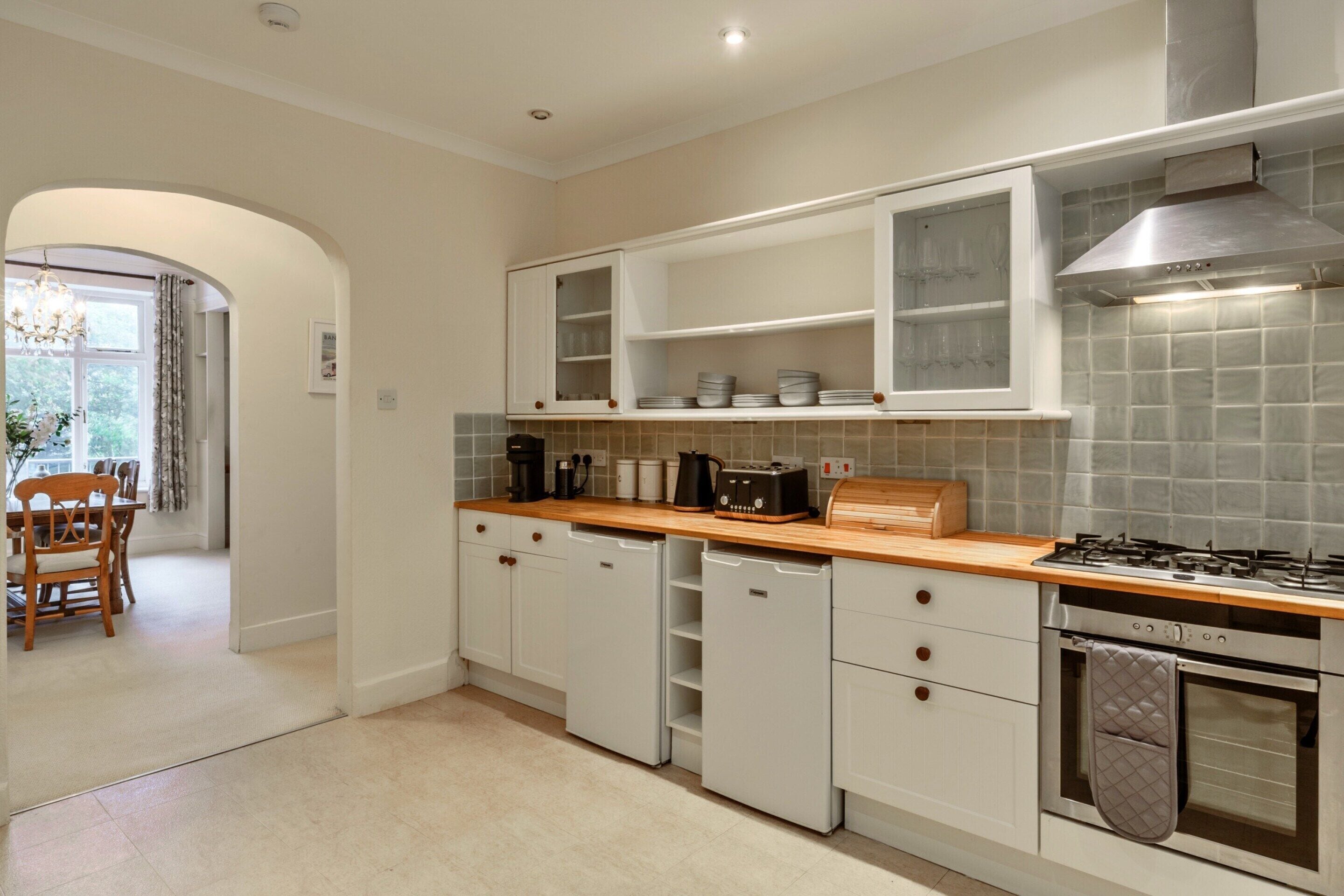 A modern kitchen with white cabinetry, a wooden countertop, a gas stove, and a built-in oven.