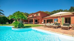 A two-story house with a swimming pool, outdoor lounge chairs, and a palm tree. - Villa 'Maison Rouge - Esprit Du Sud' with Sea View, Private Pool and Wi-Fi (Sainte-Maxime)