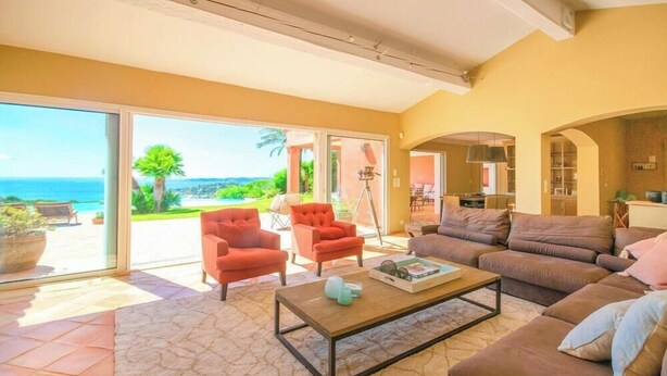 A spacious living room with a large sliding glass door leading to a balcony, a sofa, armchairs, and a coffee table. - Villa 'Maison Rouge - Esprit Du Sud' with Sea View, Private Pool and Wi-Fi (Sainte-Maxime)