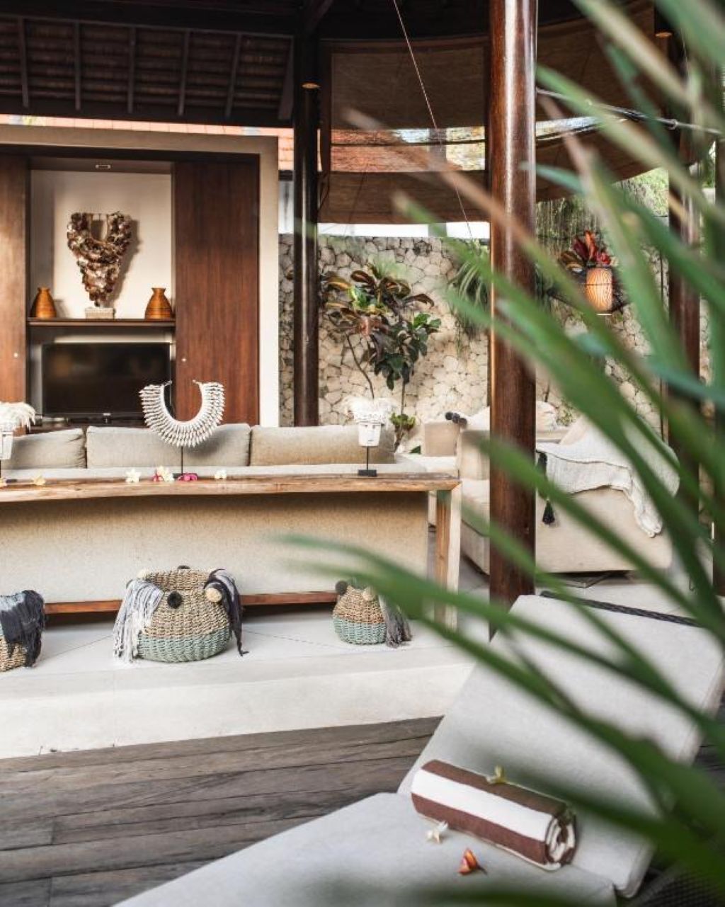 A cozy living area with a sofa, a coffee table, and decorative items. There is a stone wall and a plant in the background.
