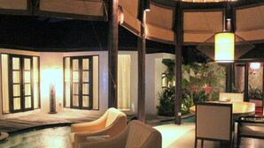 An indoor pool area with seating, a table, and a lamp. - Sandi Kala Villas - Two-Bedroom Villa (Badung Regency)