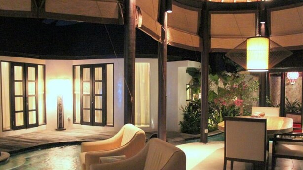 Un espace piscine intérieure aménagé avec des sièges, une table et une lampe.