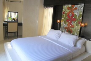 Ein Hotelzimmer mit einem Bett, einem Schreibtisch und einem Sessel. Ein Fenster mit Vorhängen, ein Bild an der Wand und eine Lampe sind ebenfalls vorhanden.