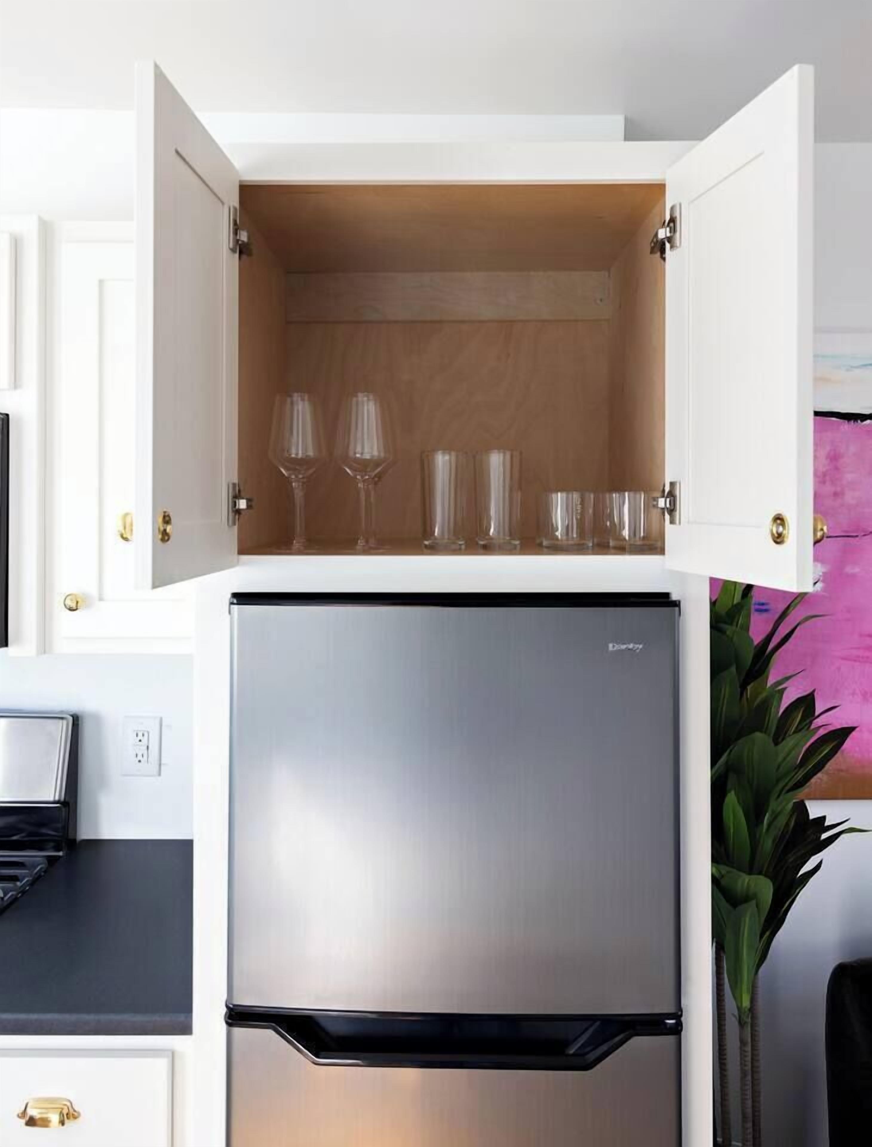 A kitchen with a built-in refrigerator and a cabinet with wine glasses.