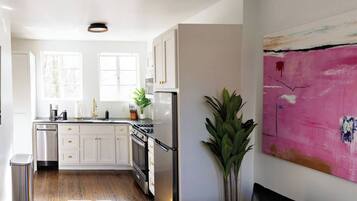 A modern kitchen with white cabinetry, stainless steel appliances, and a large window providing natural light.