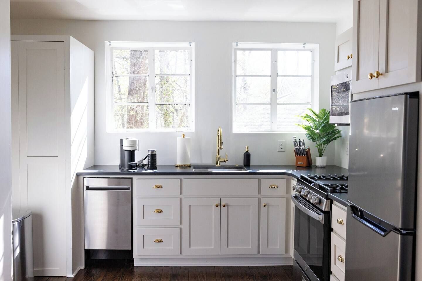 A kitchen with white cabinets, a stainless steel refrigerator, a dishwasher, and a double sink.