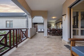 A spacious balcony with a wooden railing, a tiled floor, and a view of the sky.