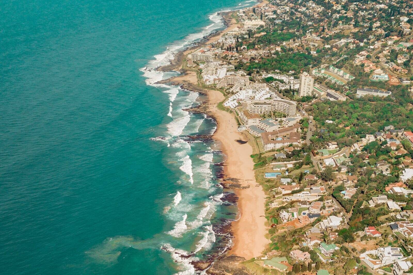Vista aérea de una zona costera con playa, edificios residenciales y un complejo hotelero.