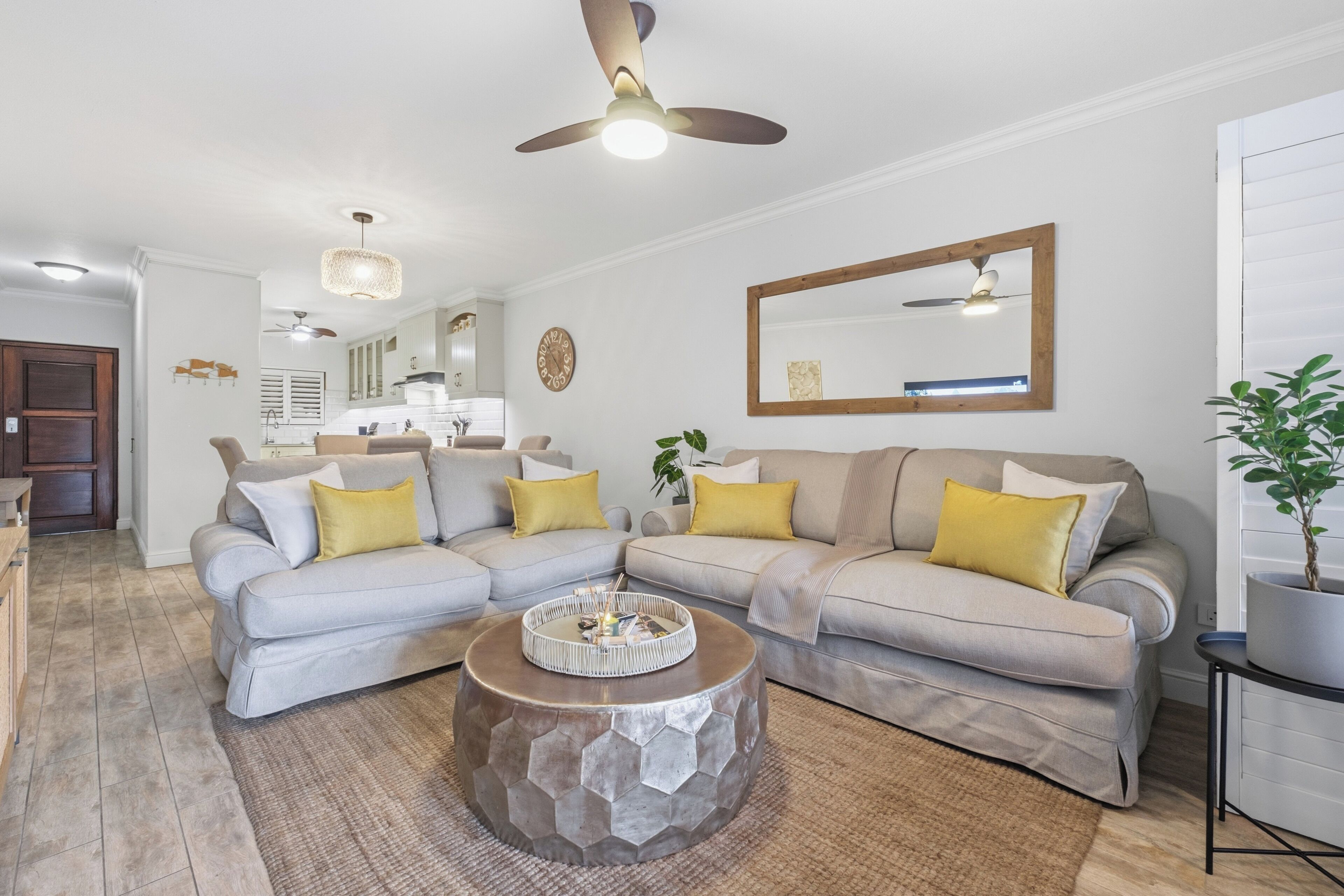 A modern living room with a sectional sofa, a coffee table, and a ceiling fan.