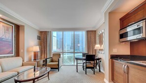 Ein Hotelzimmer mit Sitzecke, einem Esstisch, einer Küche mit Mikrowelle und einem großen Fenster mit Blick auf die Stadt.