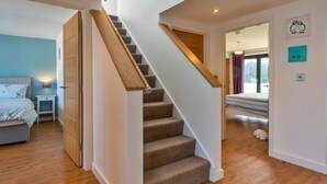 A staircase with carpeted steps leading to a bedroom with a bed and a nightstand. - Westward Ho Seaside Stay ( (Bideford)