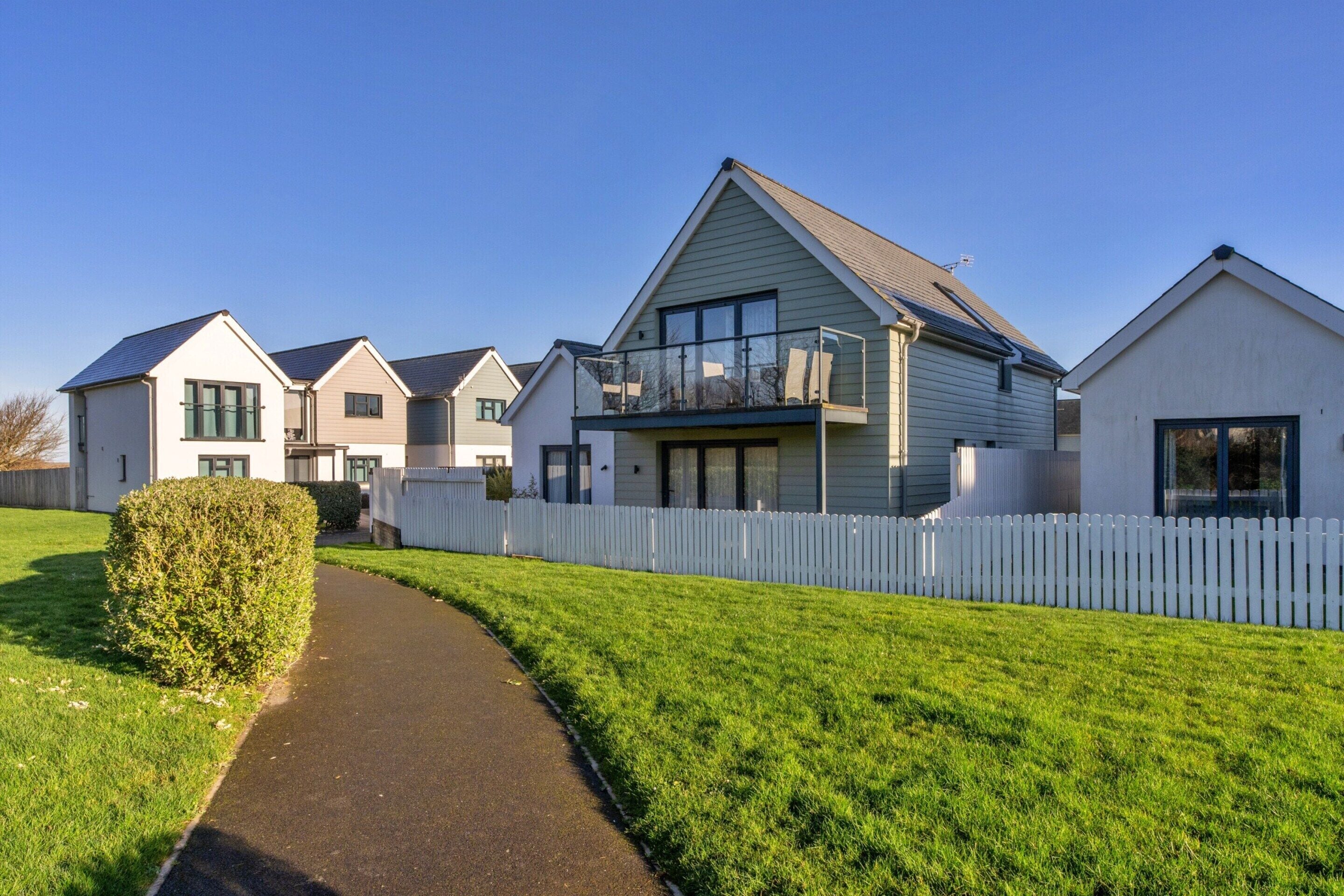A residential area with multiple houses, a pathway, and a white picket fence.
