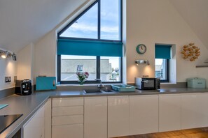 A modern kitchen with a large window, a sink, a coffee machine, and a microwave. - Westward Ho Seaside Stay ( (Bideford)