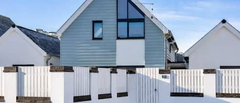 Une maison moderne à deux étages, avec une façade blanche et un toit bleu.
