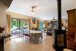 Un amplio espacio de sala con mesa de comedor, sillas, chimenea y ventilador de techo.