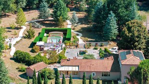 Un barrio residencial con una casa grande de techo de tejas, piscina y jardín bien cuidado.
