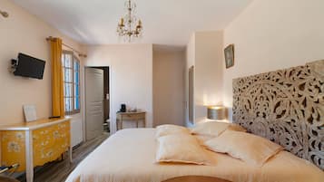 Una camera d'albergo con un letto, una scrivania, una sedia, una televisione e un lampadario.