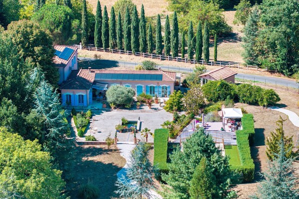 A large villa with a spacious patio, a swimming pool, and a well-maintained garden.