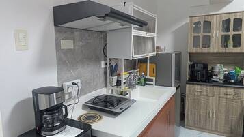 A compact kitchen with a built-in stove, coffee maker, and wooden cabinets.
