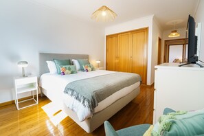 Ein Schlafzimmer mit Bett, Nachttischen, einem Kleiderschrank, einem Fernseher und einem Schreibtisch.
