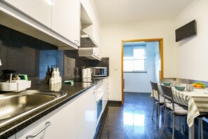 Eine moderne Küche mit einer Edelstahlspüle, einer Mikrowelle und einem Essbereich mit einem Tisch für zwei Personen.