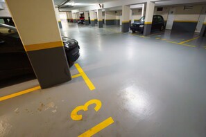 Eine mehrgeschossige Parkgarage mit markierten Stellplätzen und einem sichtbaren Auto auf einem Platz.