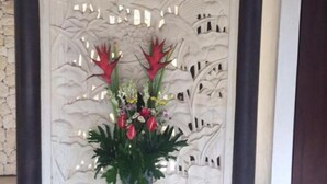 Paredes decorativas com esculturas detalhadas e um vaso com flores vermelhas.