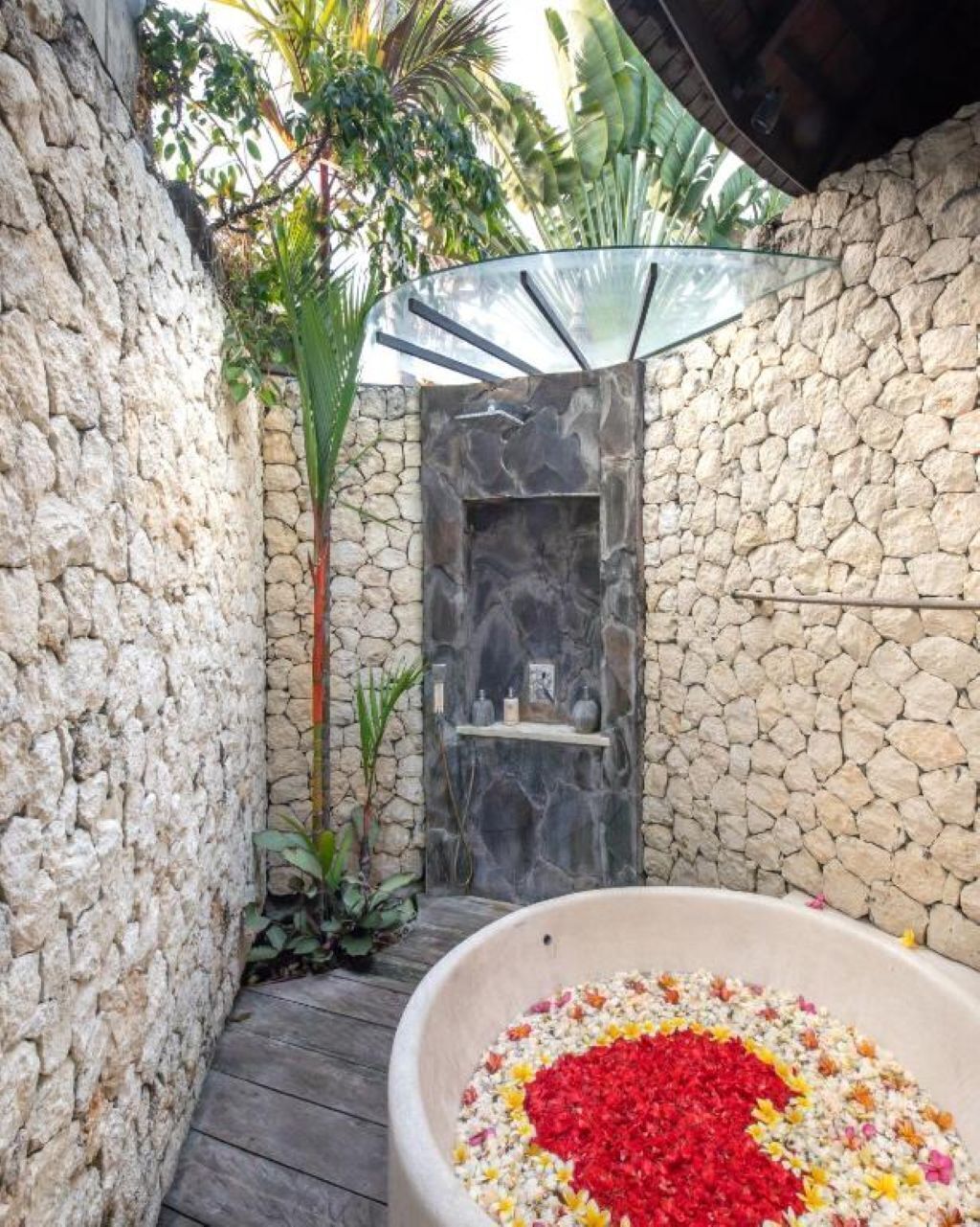 A stone-walled outdoor area with a glass door leading to a shower.