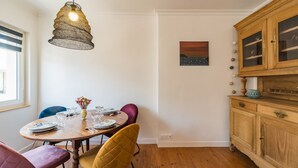 Ein Essbereich mit einem Holztisch, gedeckt für vier Personen, einer Hängelampe und einem Gemälde an der Wand.
