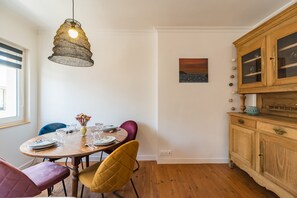 A dining area with a wooden table set for four, a hanging light fixture, and a painting on the wall. - Le Roz Cocoon - Hypercentre à 10mn de la plage (Perros-Guirec)